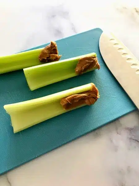 clean eating snacks, celery with peanut butter on a blue cutting board