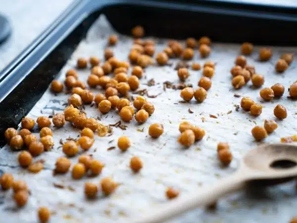 roasted chickpeas on baking sheet with wooden spoon