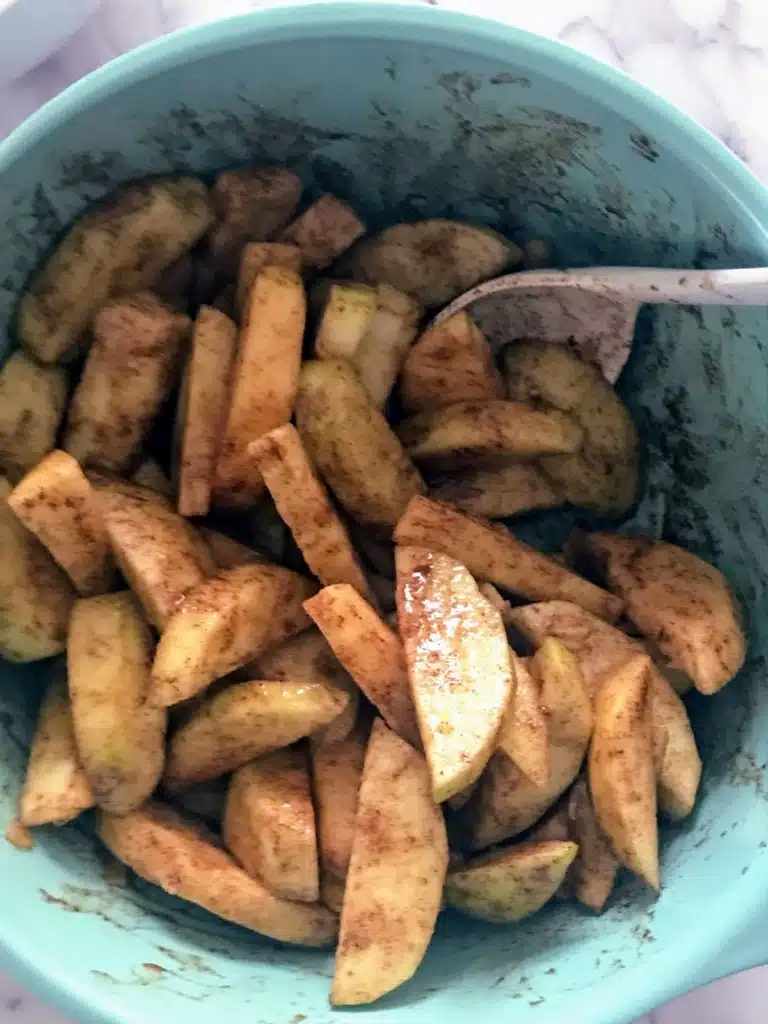 sliced apples with cinnamon in a mixing bowl.