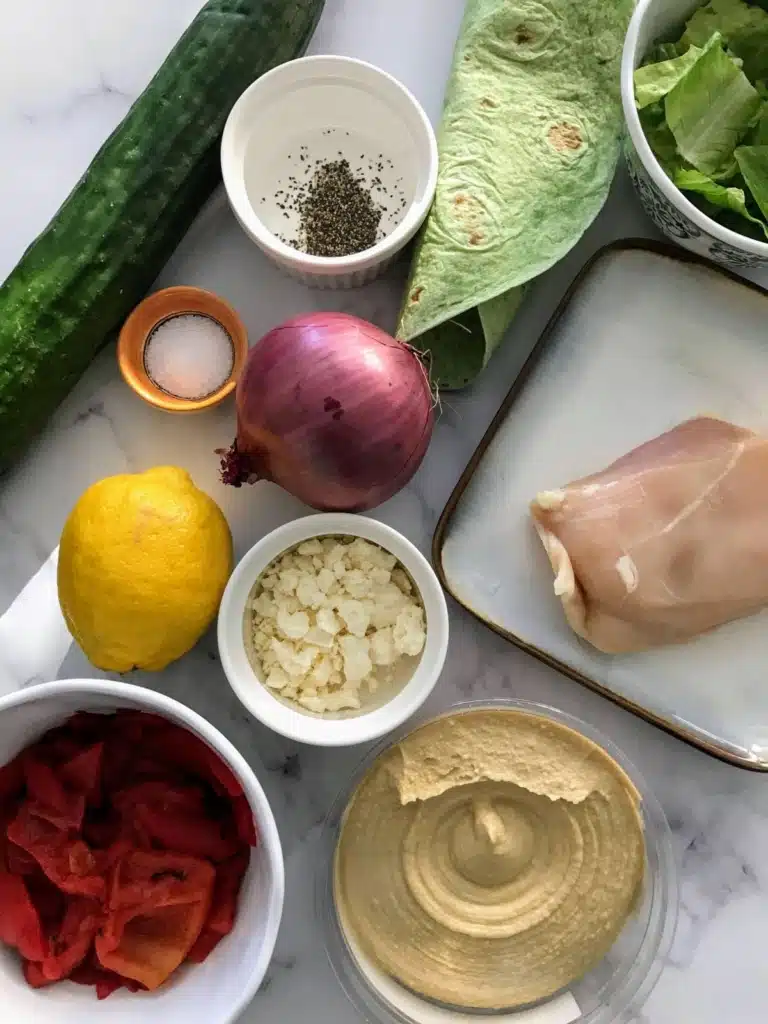 ingredients in the Mediterranean wrap, cucumber, salt, red onion, chicken breast, spinach wrap, lemon, feta cheese, red bell peppers, hummus