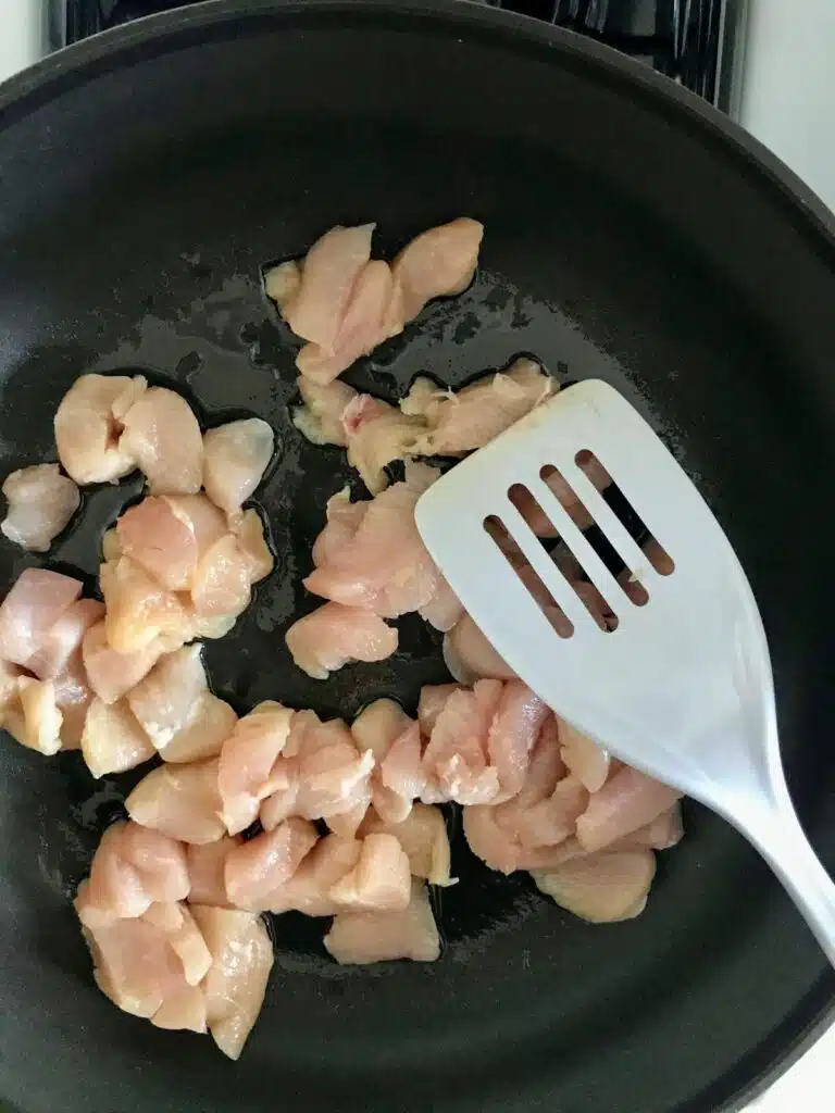 raw, chopped chicken breast in a skillet with olive oil