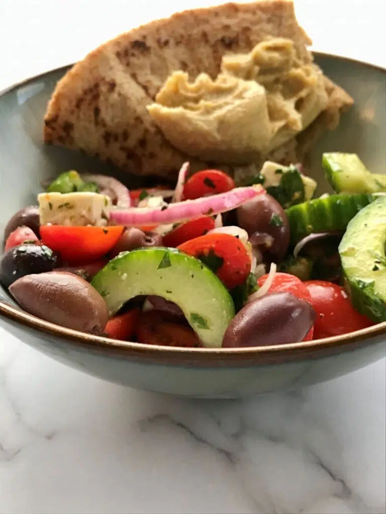 peasant salad and naan bread with hummus in a bowl.