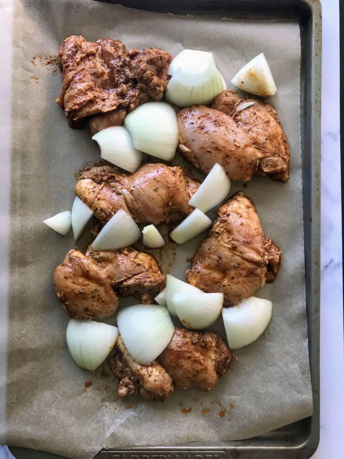 marinated raw chicken, cut raw onions on a sheet pan.
