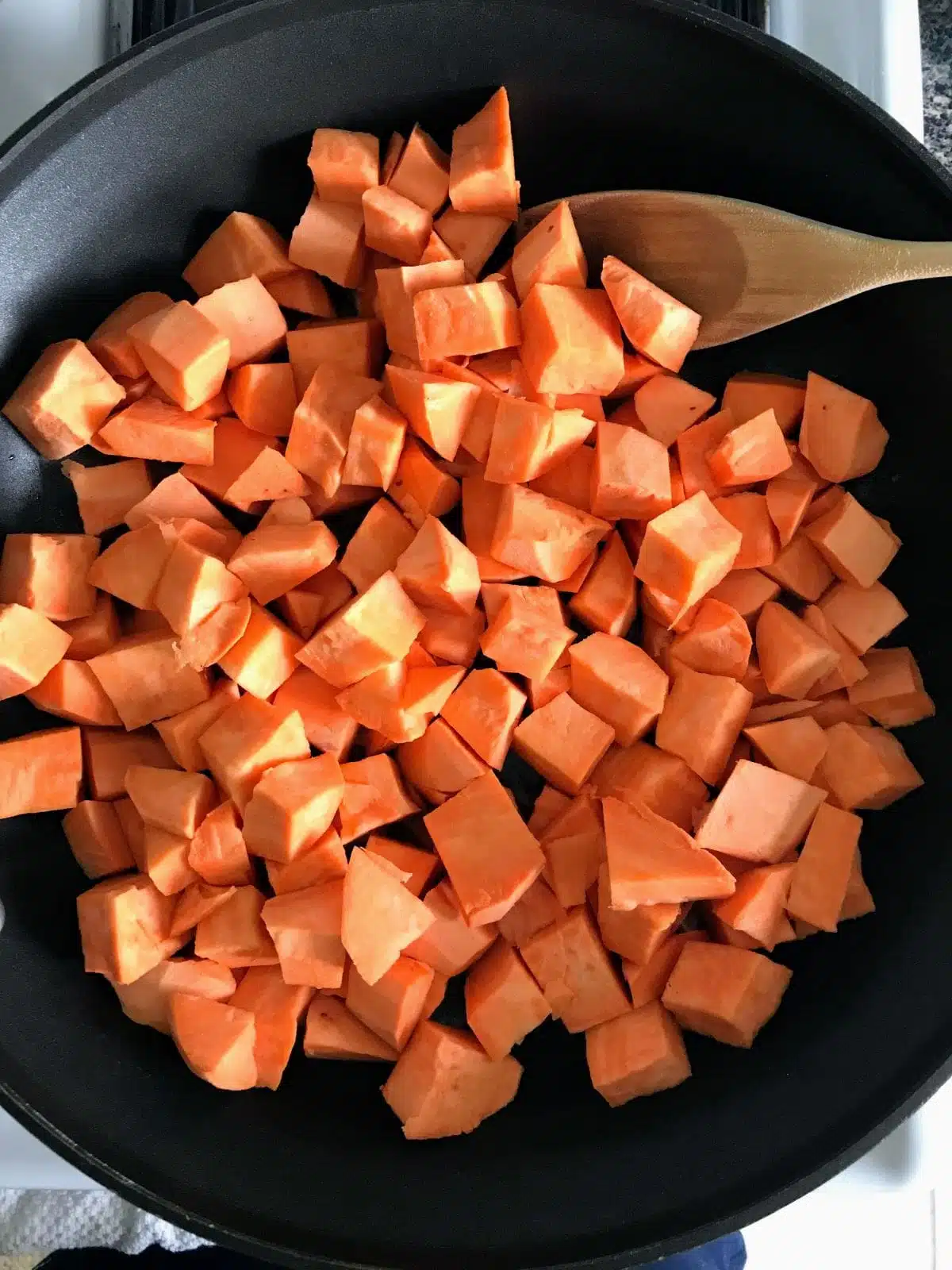 raw chopped sweet potatoes in a skillet.