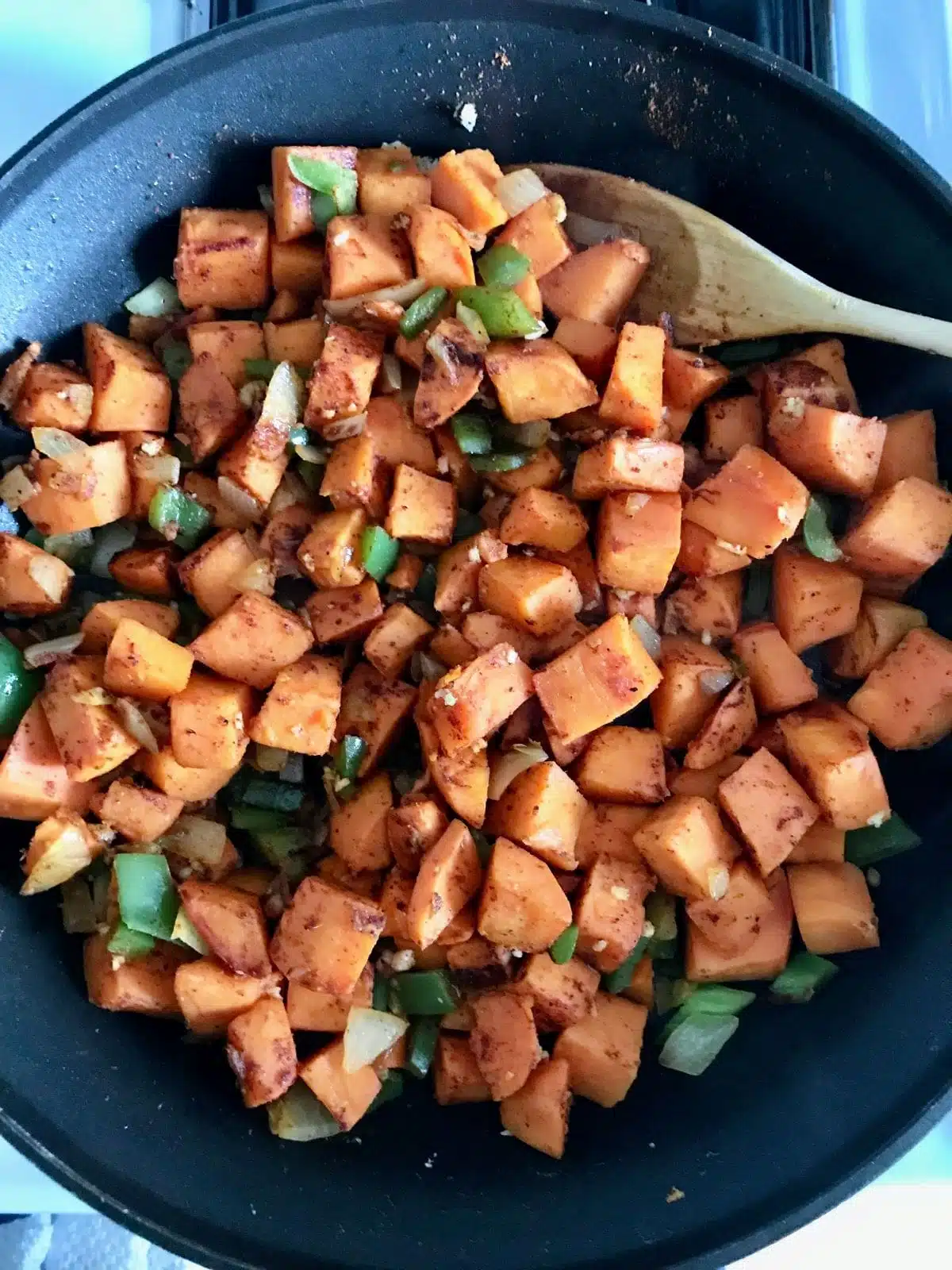chopped sweet potatoes, green bell peppers, onion, and garlic in a skillet.