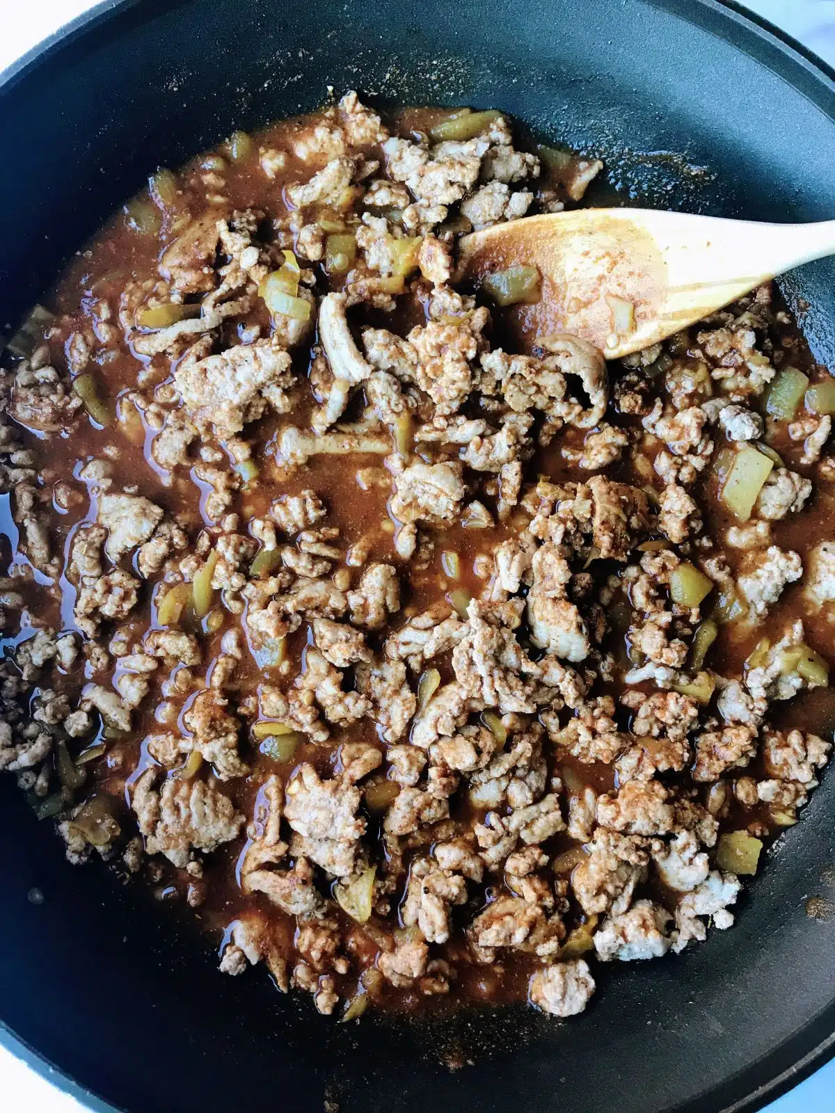 Ground turkey cooking in spices, tomato sauce, and mild green chiles.