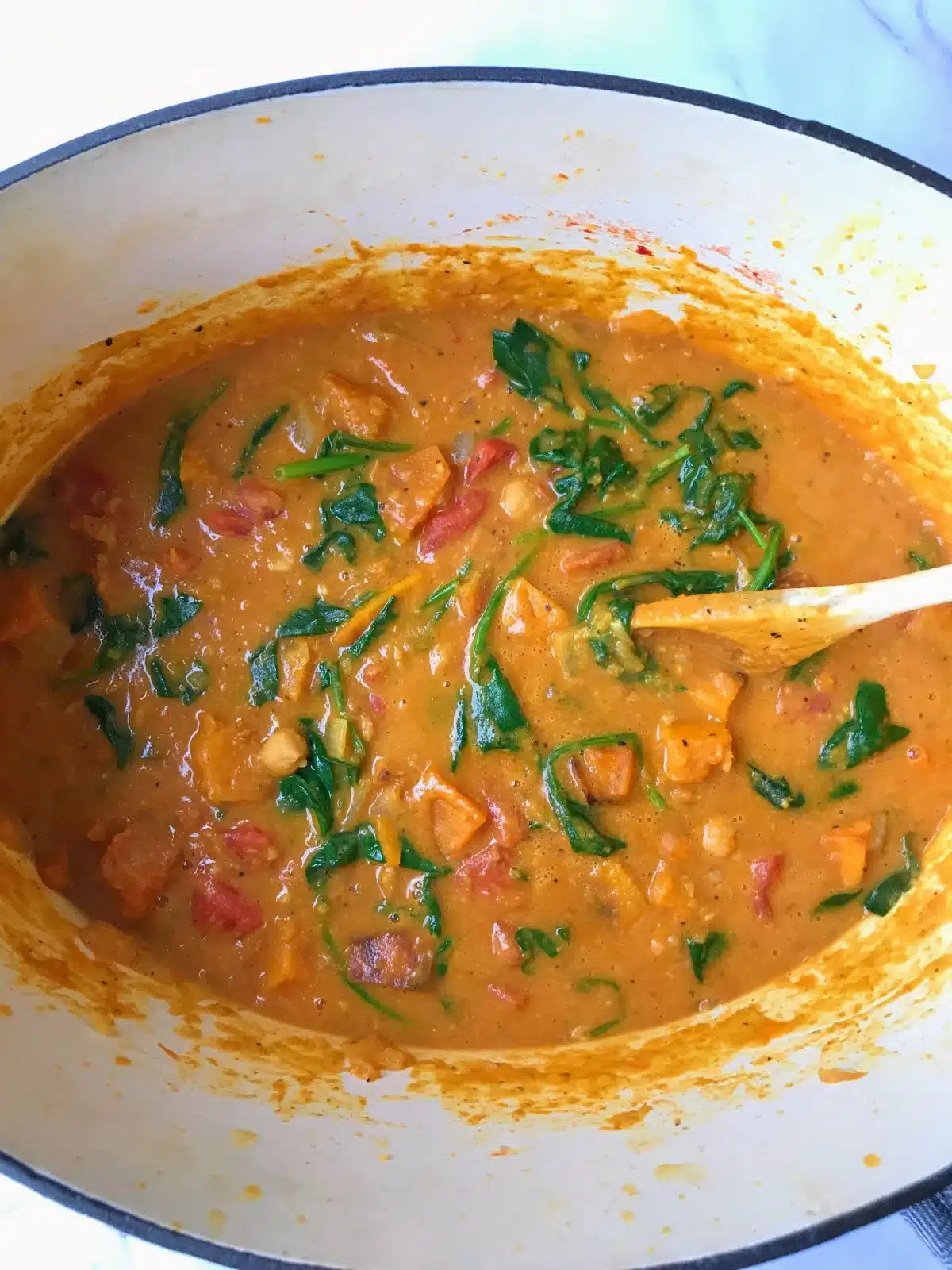 Butternut squash and chickpea curry with spinach in a Dutch oven.