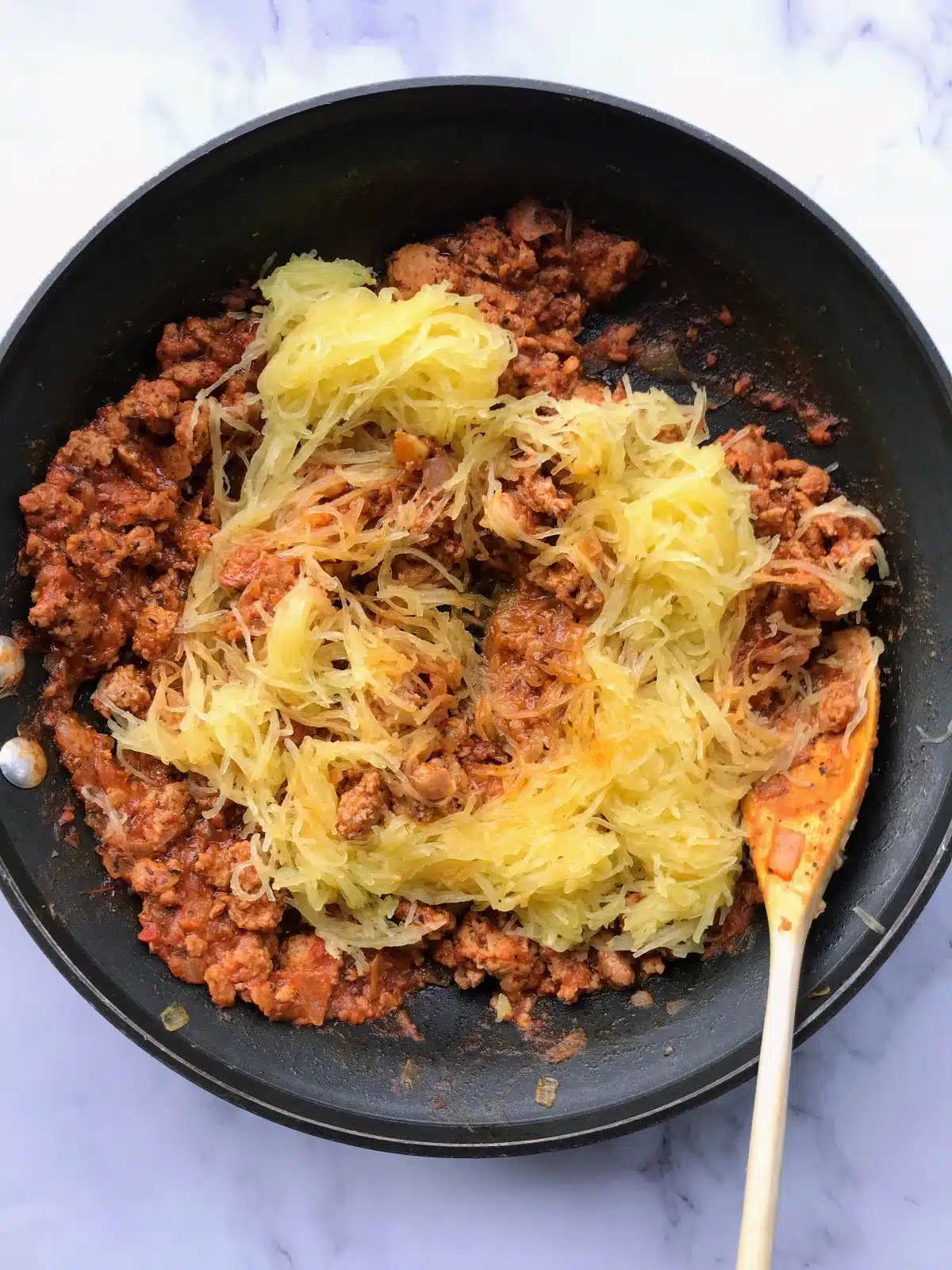 Spaghetti squash strands added to skillet with Italian sausage.