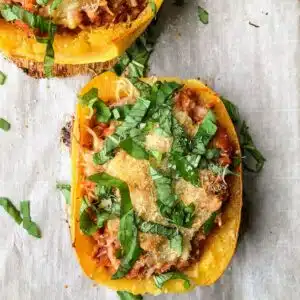Stuffed spaghetti squash on baking sheet with parchment paper.